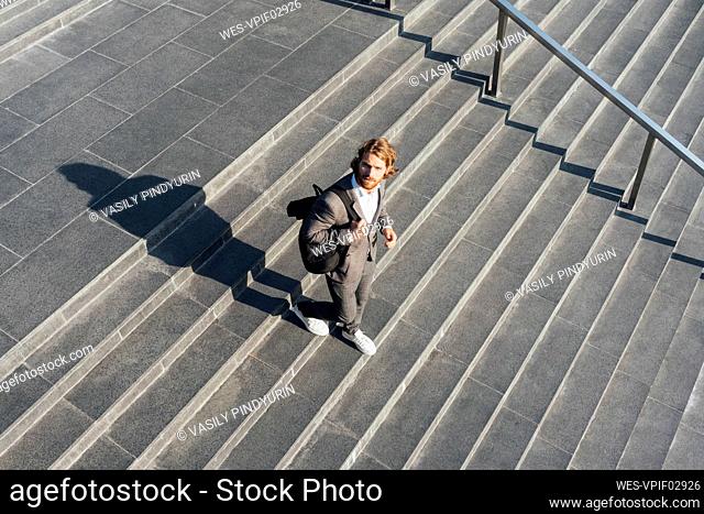 Male professional with bag moving down on staircase in downtown during sunny day