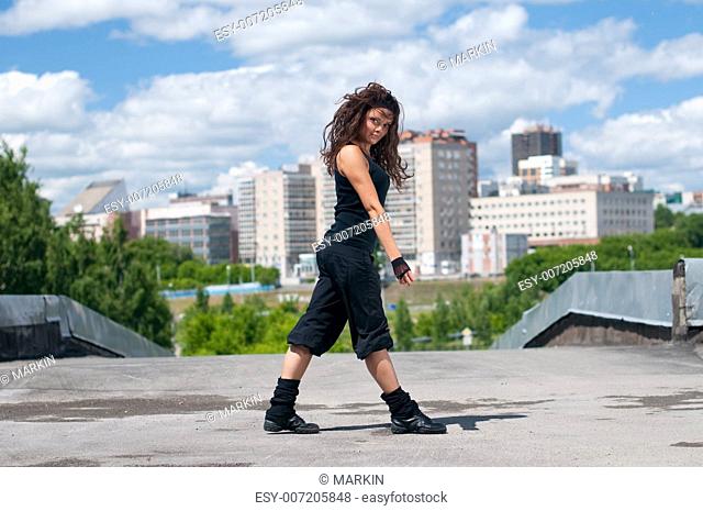 Beautiful teenage girl dancing in modern style over urban city landscape