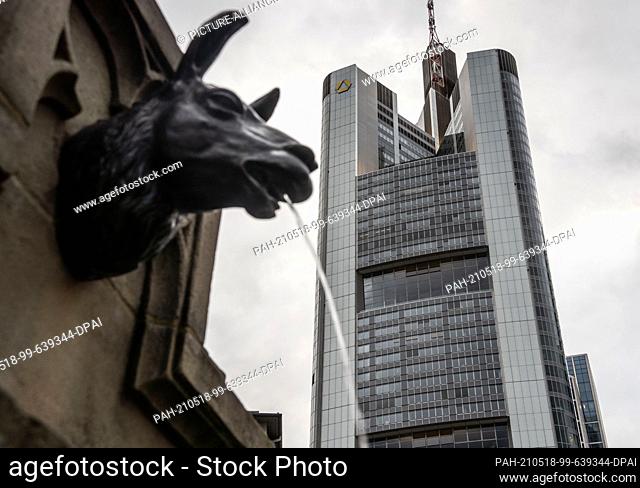17 May 2021, Hessen, Frankfurt/Main: Commerzbank's head office stands next to a gargoyle on the Gutenberg Monument, which is in the shape of a llama's head and...