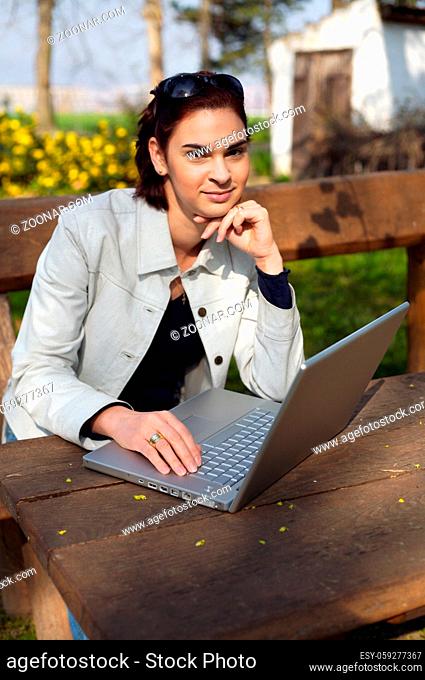 Young woman works on a laptop computer outdoor