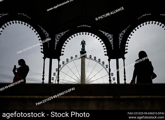 25 October 2023, Baden-Württemberg, Stuttgart: A woman with a smartphone and a woman with a headscarf are standing in the music pavilion on Schlossplatz