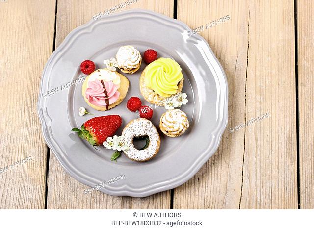 Top view of assorted cookies and fruits on grey ceramic plate
