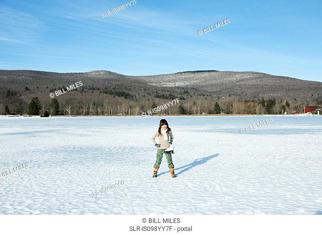 Girl standing in snow with ice skates