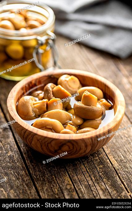 Pickled champignons. Marinated mushrooms in wooden bowl