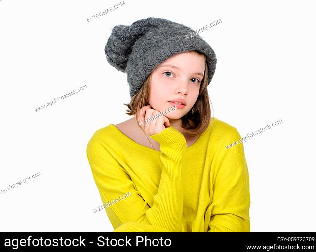 Portrait of a cute teen girl in a warm knitted hat and a bright yellow sweater