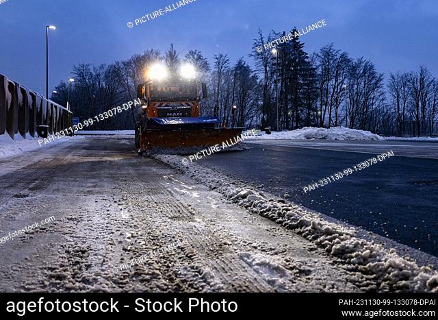 30 November 2023, North Rhine-Westphalia, Lüdenscheid: An Autobahn GmbH snow clearing vehicle clears snow from the parking lots and roadways in a parking lot on...