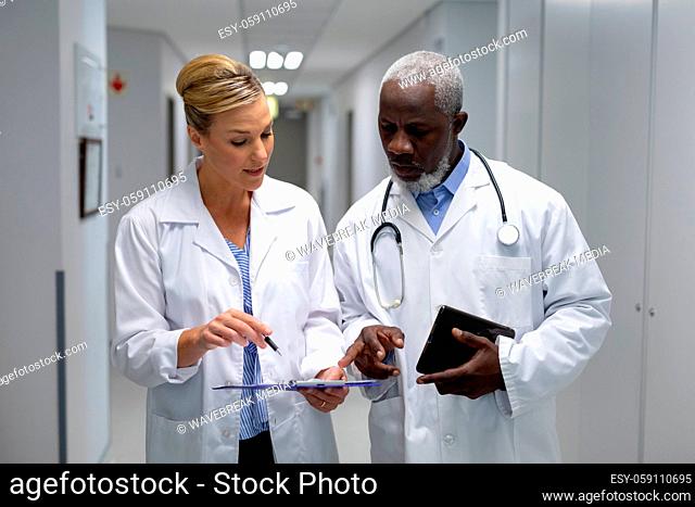 Diverse male and female doctors standing in hospital corridor looking at medical chart document