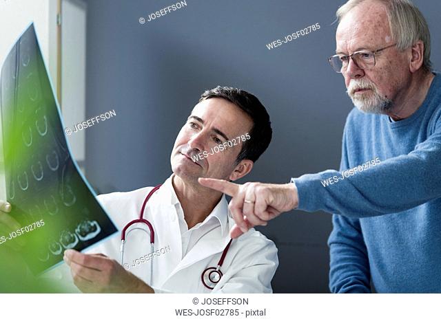 Doctor discussing MRT image with senior patient in medical practice