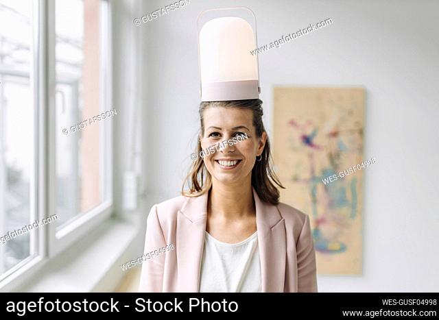 Portrait of smiling businesswoman with lantern in head in office