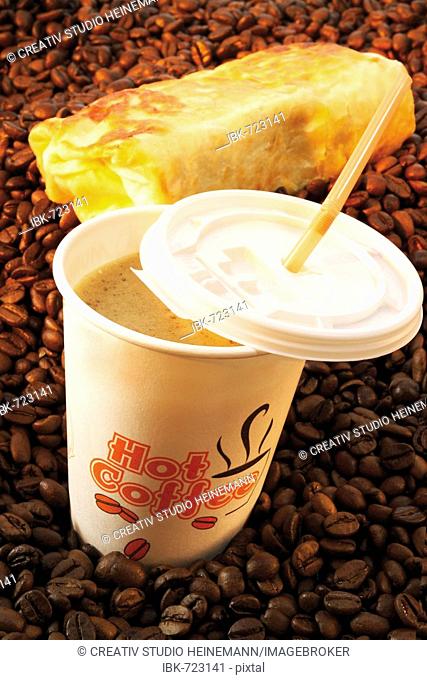 Coffee to go: paper cup filled with coffee on a layer of coffee beans