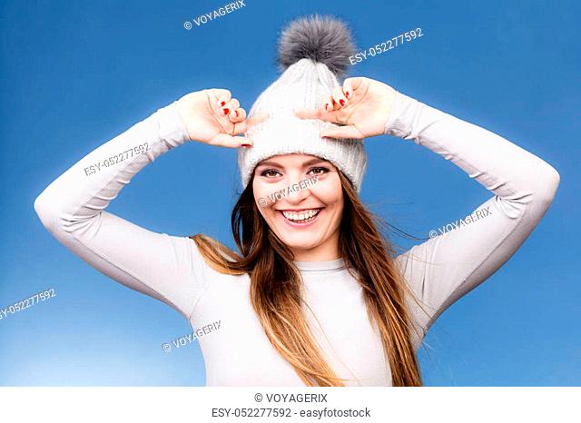 Attractive woman in winter cap and gray sports thermolinen underwear for skiing training studio shot on blue. Long sleeves top