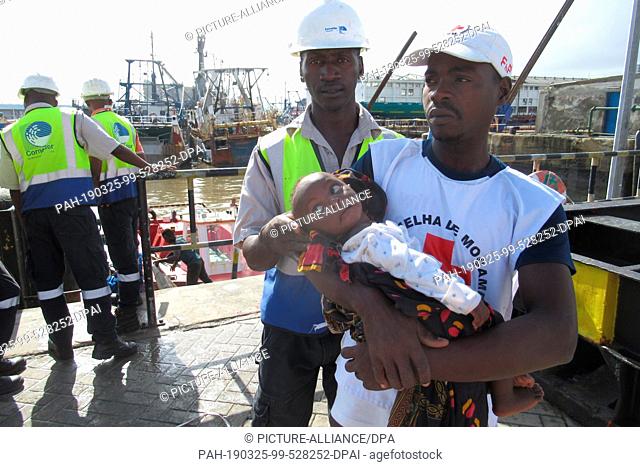 23 March 2019, Mozambique, Beira: A man holds a toddler after a lifeboat moors in Beira harbour. (to dpa ""Helpers in Mozambique warn against diseases after...