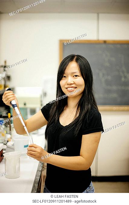 Woman in laboratory with pipette filler and glass tube
