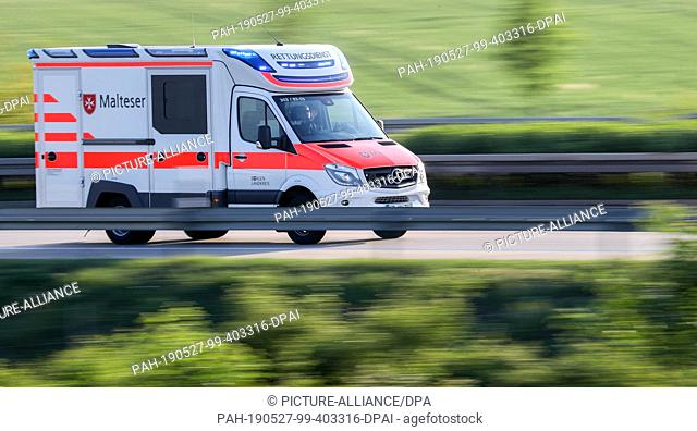 19 May 2019, Saxony-Anhalt, Leuna: A Malteser ambulance drives with blue light from the scene of the accident with a coach