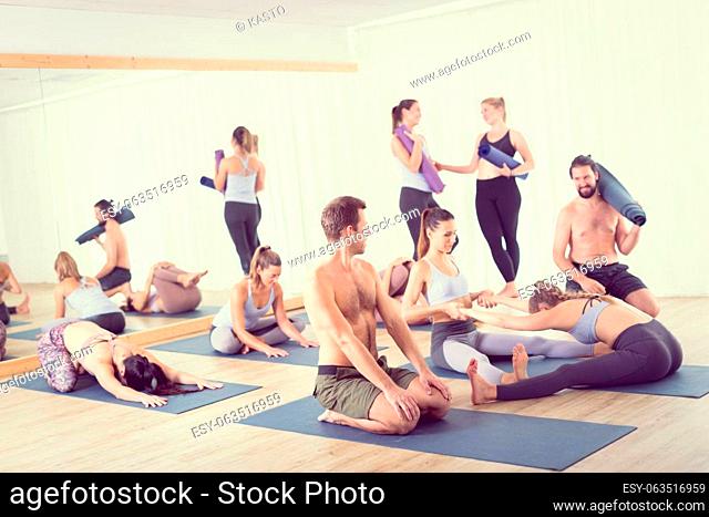 Group of young sporty attractive people in yoga studio, relaxing and socializing after hot yoga class. Healthy active lifestyle, working out indoors