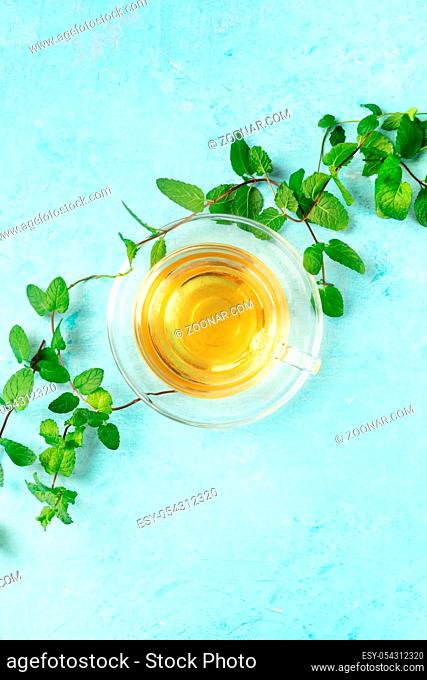 Mint tea cup, overhead shot on a blue background with fresh mint leaves and a place for text