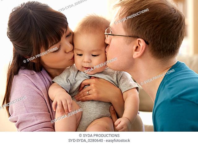 happy mother and father kissing baby son at home