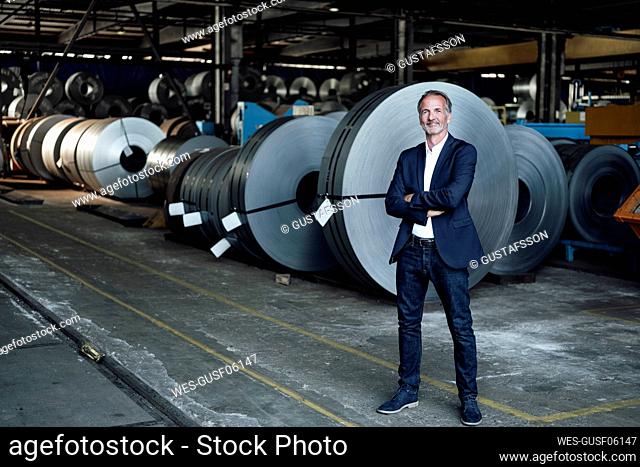 Senior businessman with arms crossed standing at warehouse