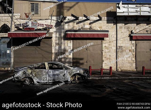 12 May 2021, Israel, Lod: A burnt car is seen after the riots in the city of Lod, following the funeral of a 25-year-old Israeli-Arab man who was shot and...