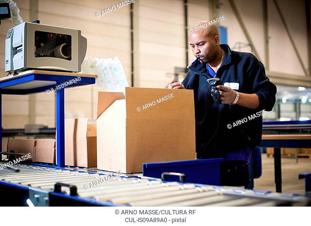 Male warehouse worker checking cardboard box