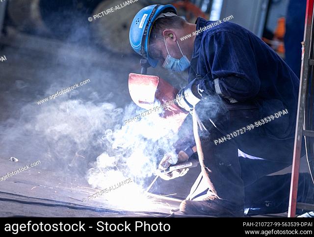 14 July 2021, Mecklenburg-Western Pomerania, Wismar: A shipbuilder welds on one of the decks in the ""Global Dream"" cruise ship under construction in the dock...