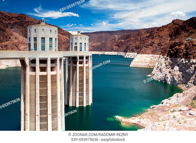 Hoover Dam Towers on the blue Lake Mead. Hoover Dam is a concrete arch-gravity dam in the Black Canyon of the Colorado River, on the border between the U