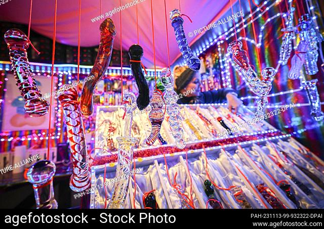 13 November 2023, Hamburg: Glass dildos hang from a stall called ""Warm moist and delicious"" at the ""Santa Pauli"" Christmas market on Spielbudenplatz on the...