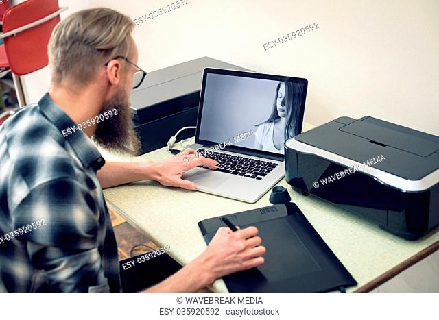 Photographer using graphics tablet while editing at table
