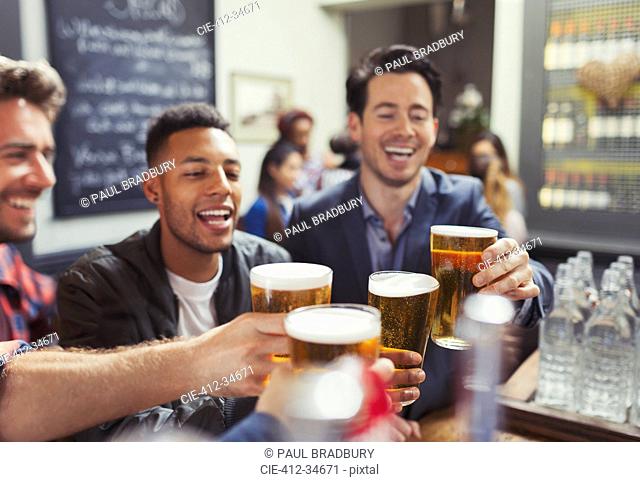 Men friends toasting beer glasses at bar
