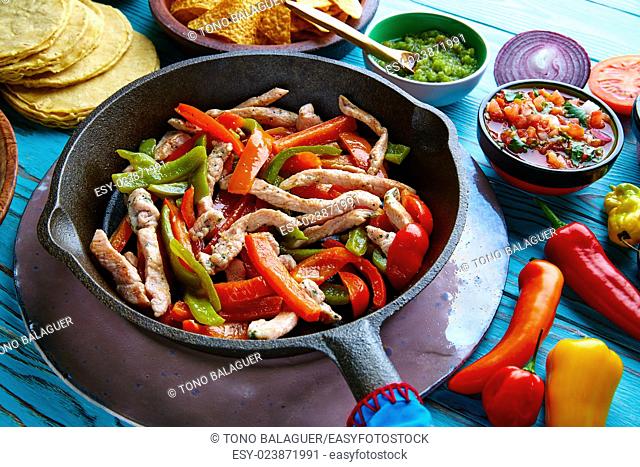 chicken fajitas in a pan with sauces chili and sides Mexican food