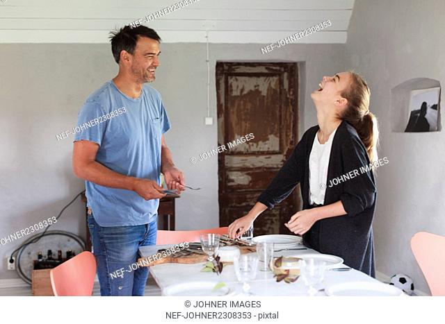 Father with teenage girl setting table
