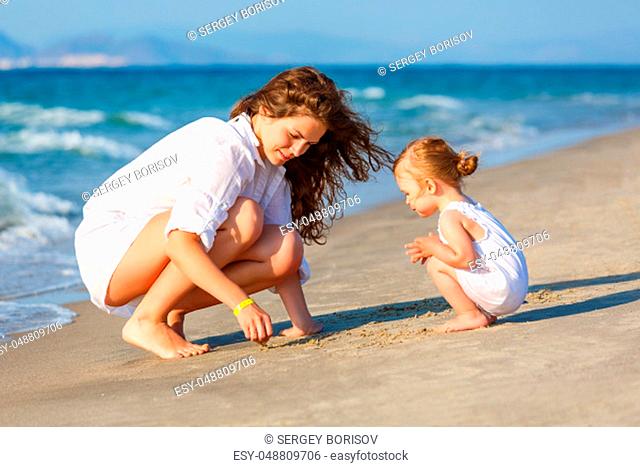 Mother and little daughter playing on the sea beach in Greece
