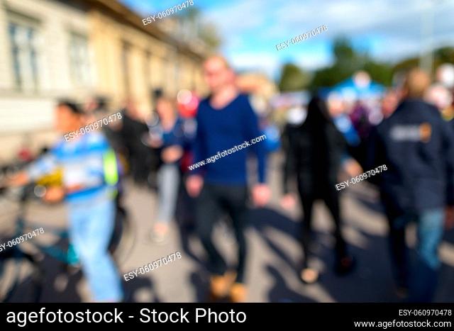 Portrait of defocused crowd of people looking busy in the city street on sunny day