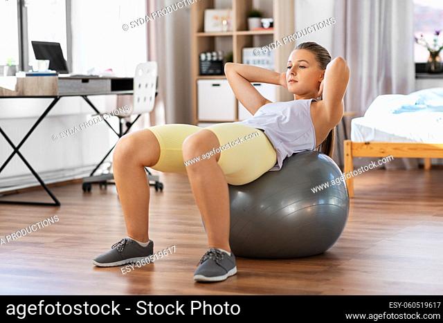 teenage girl training on exercise ball at home