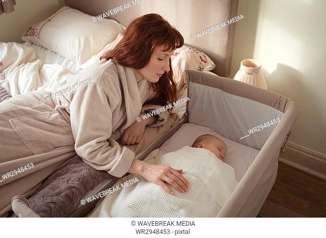 Mother watching sleeping baby in crib