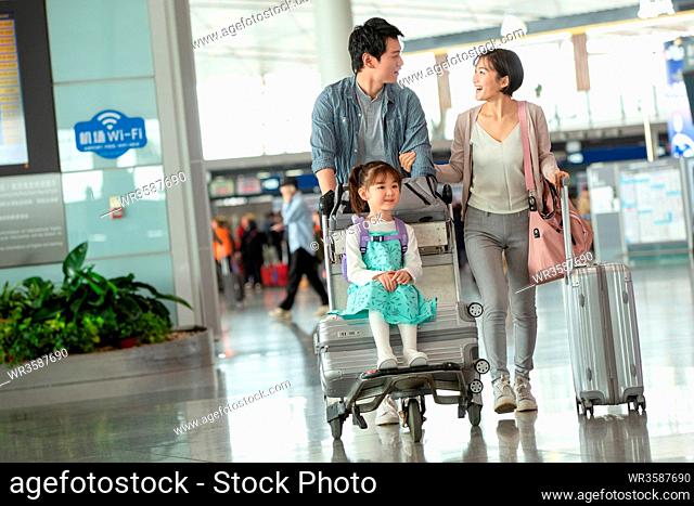 Happy family pushing baggage at the airport