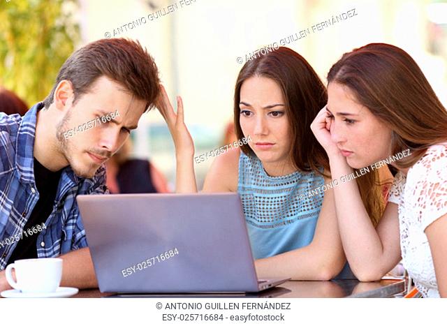 Three upset friends online using a laptop with problems in a coffee shop