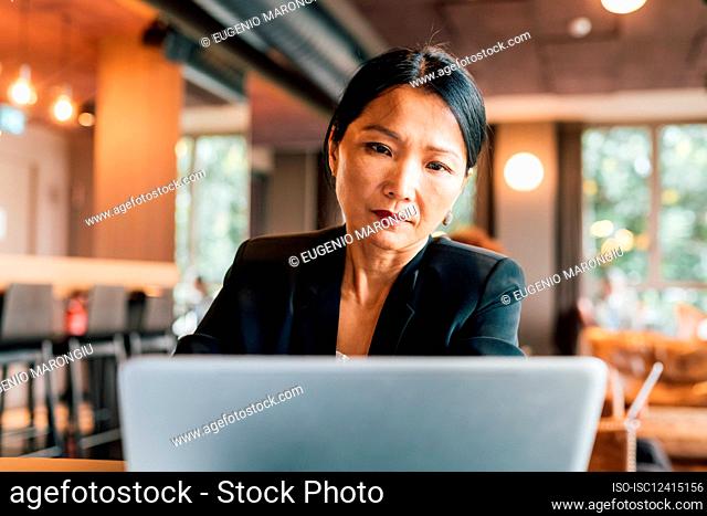 Italy, Businesswoman using laptop at table in creative studio