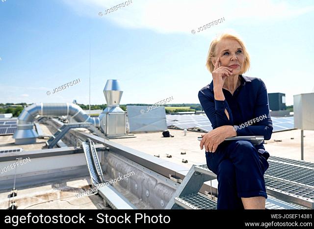 Thoughtful senior businesswoman with laptop on rooftop