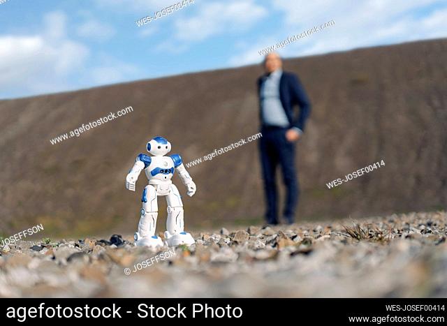 Miniature robot and businessman on a disused mine tip