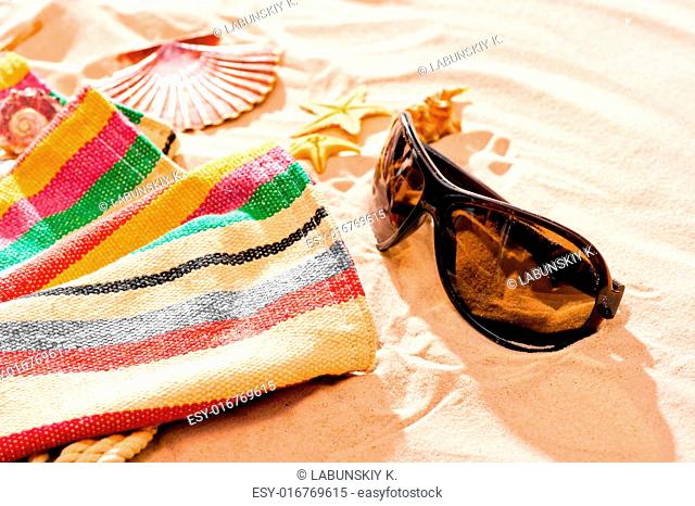 striped beach towel and sunglasses on a sandy beach