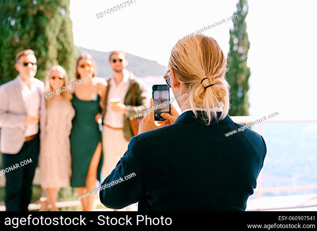 Man in a suit shoots a group of people on a smartphone against the background of the sea. High quality photo