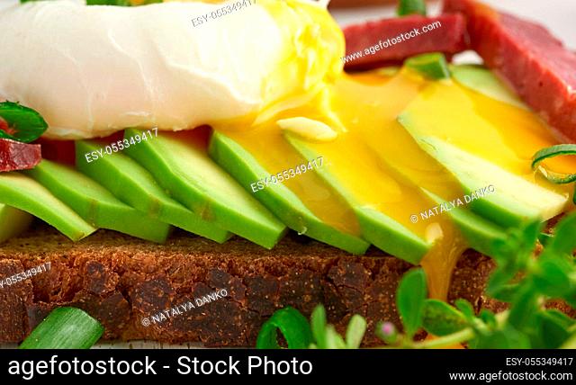 toast with poached egg and avocado on a round board, morning breakfast, close up
