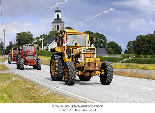 Kimito, Finland. July 6, 2019. Three Volvo BM tractors, yellow 814 first, on Kimito Tractorkavalkad, annual tractor parade through the small town