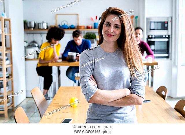 Portrait of woman at dining table at home with friends in background