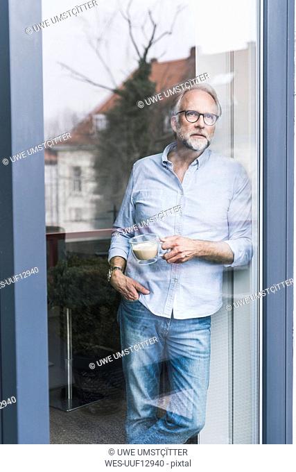 Portrait of mature man looking out of terrace door