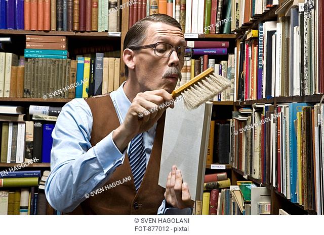 A man using a dust brush on a book
