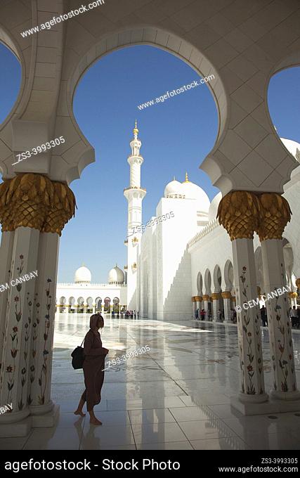Visitors between the gilded columns of Sheikh Zayed Bin Sultan Al Nahyan Mosque, Abu Dhabi, United Arab Emirates, Middle East