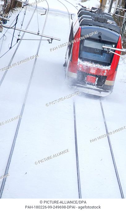 26 February 2018, Germany, Luebeck: A local train of the Deutsche Bahn (DB) (German Railway) drives on snow covered tracks to the main station of Luebeck