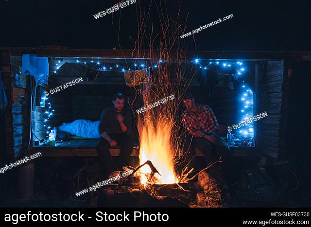 Friends sitting at campfire, staying over outdoors